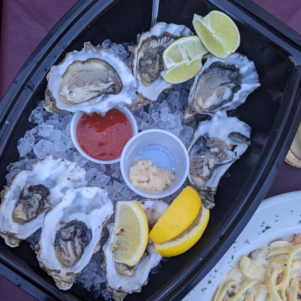 Fresh oysters on ice with lime, lemon, cocktail sauce, and horseradish, ready to be enjoyed.