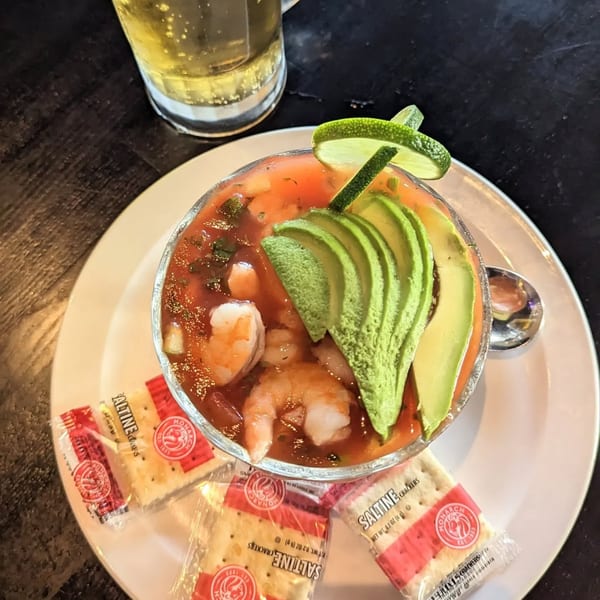 Shrimp cocktail with avocado and lime, served with saltine crackers and a beer.