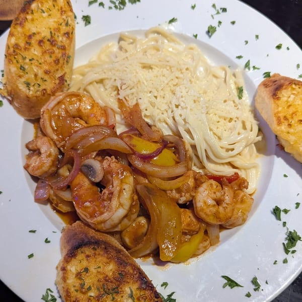 Shrimp scampi with bell peppers and onions, served with linguine Alfredo and garlic bread.